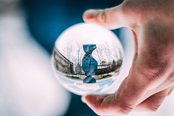 Person Holding Sphere Reflecting Dna-shaped Statue
