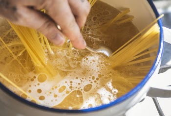 Person Holding Stainless Steel Spoon While Stirring Liquid Filled Casserole