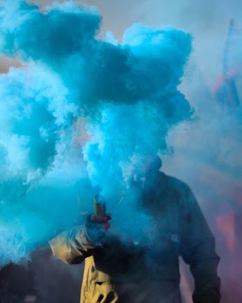person holding stick with blue smoke