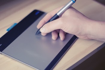 Person Holding Stylus Pen on Writing Pad