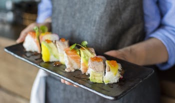 Person Holding Sushi on Black Plate