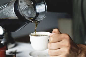 Person Holding White Ceramic Cup and Glass Pitcher