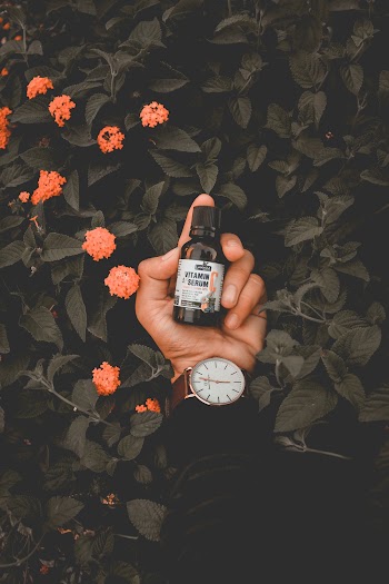 Person Holding White Labeled Small Glass Bottle