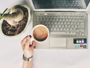Person Holding White Mug on Gray Laptop Computer