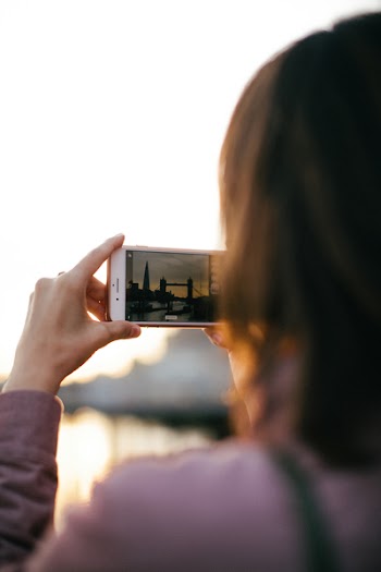 Person Holding White Smartphone While Capturing Tower Bridge at Golden Hour