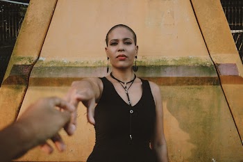 Person Holding Woman's Finger in Front of Orange Painted Concrete Wall