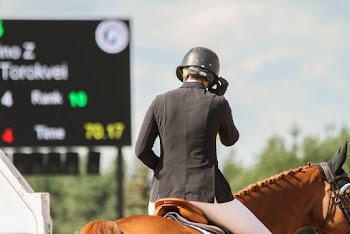 Person in Black Helmet and Black Top Riding Horse