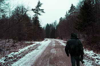 Person in Black Hoodie Top and Black Pants on the road holding a camera