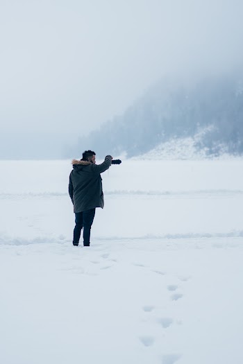 Person In Black Parka Hoodie Standing On Snow Covered Road