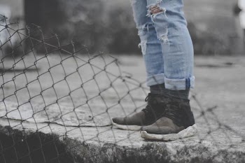 person in black running shoes beside diamond fence