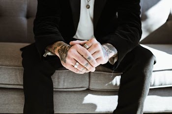 person in black suit jacket holding both hands