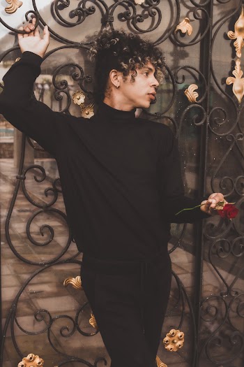Person In Black Sweater Leaning, On A Black And Gold Wrought Iron Grill
