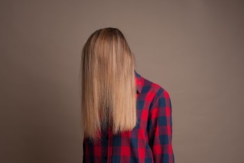 person in blue and red checkered dress shirt standing in front of gray painted wall