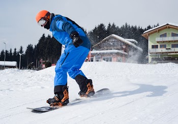Person in Blue Coveralls Snowboarding on Snow