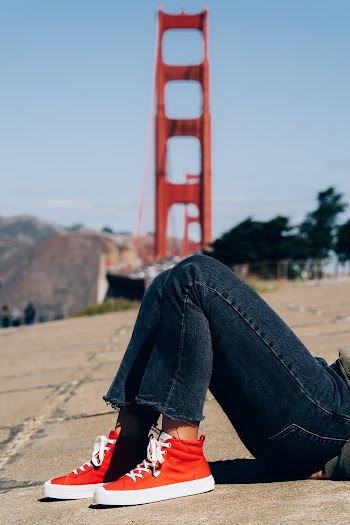 Person in Blue Jeans and Pair of Red-and-white High-top Sneakers