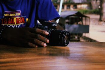 Person in Blue Printed Shirt Holding Canon Dslr Camera
