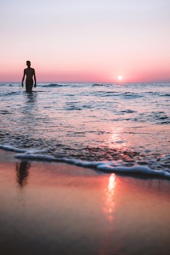 person in body of water during golden hour