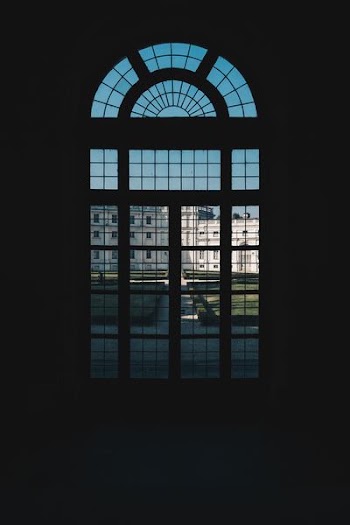 person in dark room near glass window