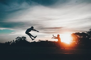 Person in Front of Man Flying Wearing Hat during Sunset