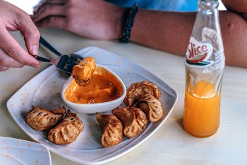 Person in Front of Table With Fried Dumplings and Soda Bottle