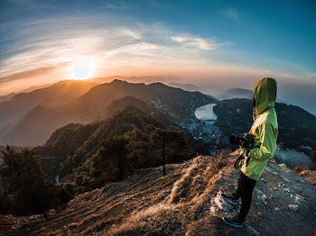 Person In Green Hoodie Standing Looking At Sunset
