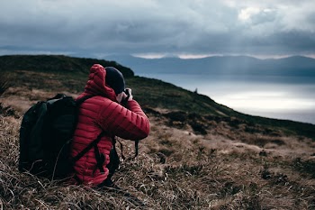 Person in Red Hoodie Taking a Photo of Wilderness
