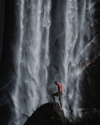 Person in Red Shirt Stepping on Rock