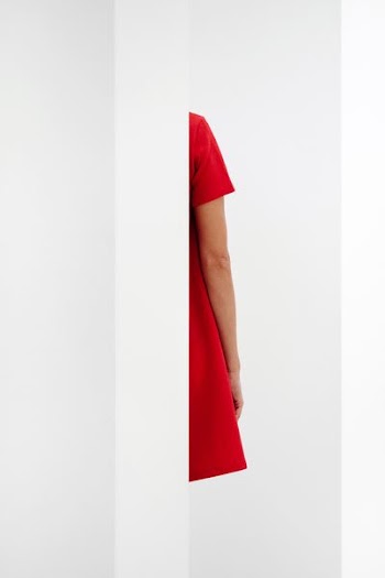 person in red top standing behind wall