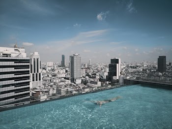 Person in Swimming Pool on Top of Building Facing High-rise and Mid-rise Buildings