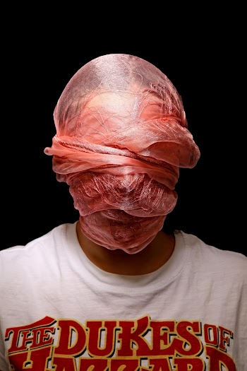 Person in t shirt covering their face with a scarf 