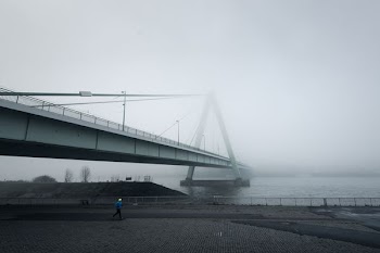 person jogging under bridge during dawn