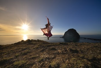 Person Jumping On Rocky Shore
