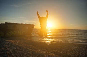 Person Jumping on Seashore during Golden Hour