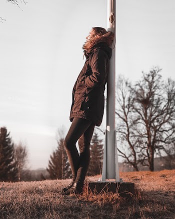 Person Leaning Backwards on White Pole
