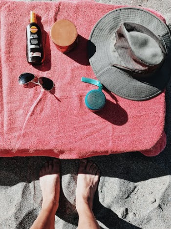 Person Legs with Summer Essentials on Beach