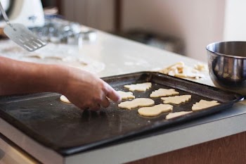 person lining assorted-shaped cookies on baking sheet inside kitchen