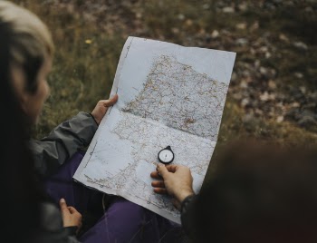 Person Looking At The Map And Using Compass
