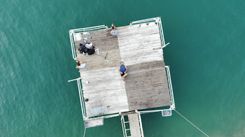 Person Lying on Brown Wooden Platform on Body of Water