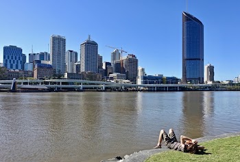 Person Lying on Green Grass Near Body of Water