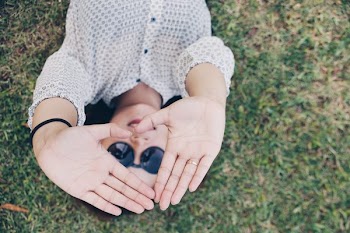 Person Lying on Green Grass While Raised Hands