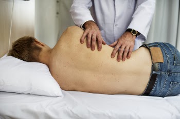 Person Massaging Man While Lying on Bed
