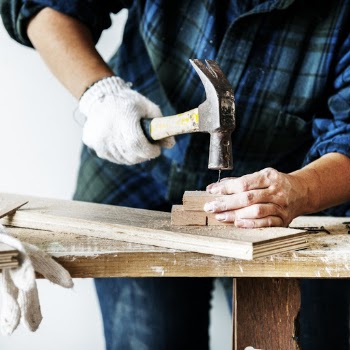 Person Nailing A Block Of Wood On A Plank