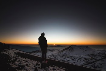 person on top of mountain looking at sunset