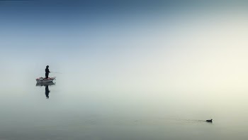 Person on White Boat Fishing on Body of Water