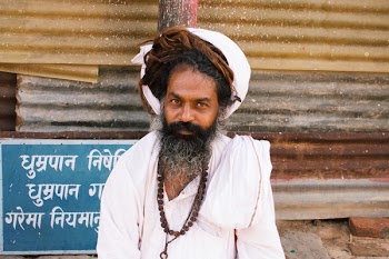 Person on White Tops Sitting on Ground Near Brown Post