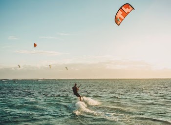 person parasailing on body of water under blue sky during daytime