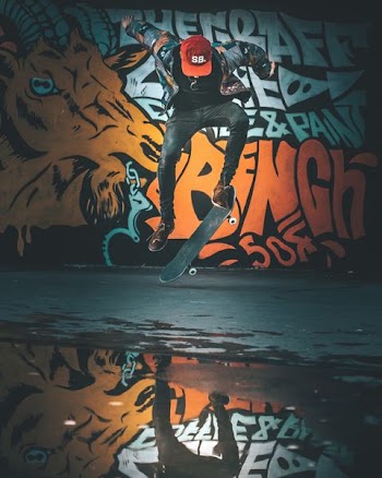 person performing skateboard trick near wall with graffiti