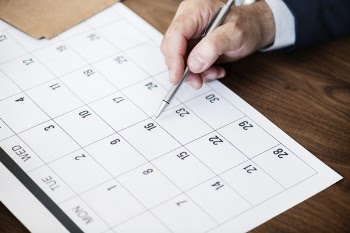 Person Pinpointing Pen on Calendar
