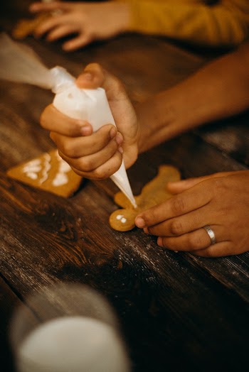Person Piping Icing on Gingerbread Cookie