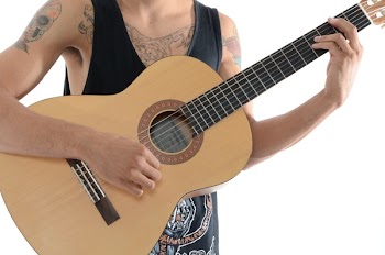 Person Playing a Classic Acoustic Guitar in a White Room